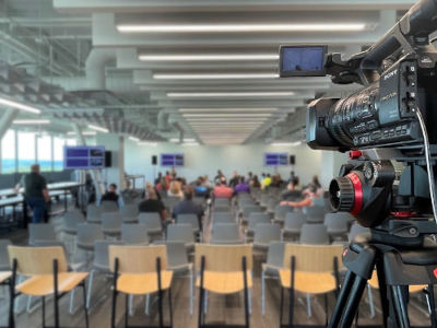 Conference room set up with chairs, multiple TV monitors, speakers and camera